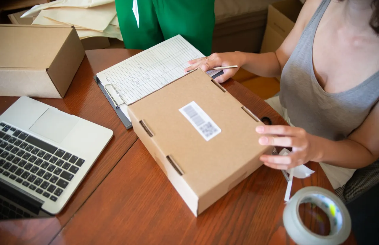 Small-business owner preparing an online order beside a laptop